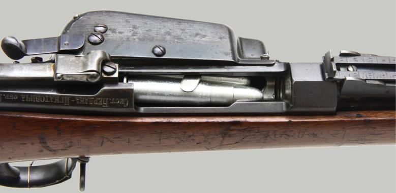 Ил. 10. Вид внутренней части ствольной коробки и наполненного патронами магазина; на снимке видна ложка, удерживающая патроны от выпадения при стрельбе лежа на спине или на боку Ил. 10. Вид внутренней части ствольной коробки и наполненного патронами магазина; на снимке видна ложка, удерживающая патроны от выпадения при стрельбе лежа на спине или на боку